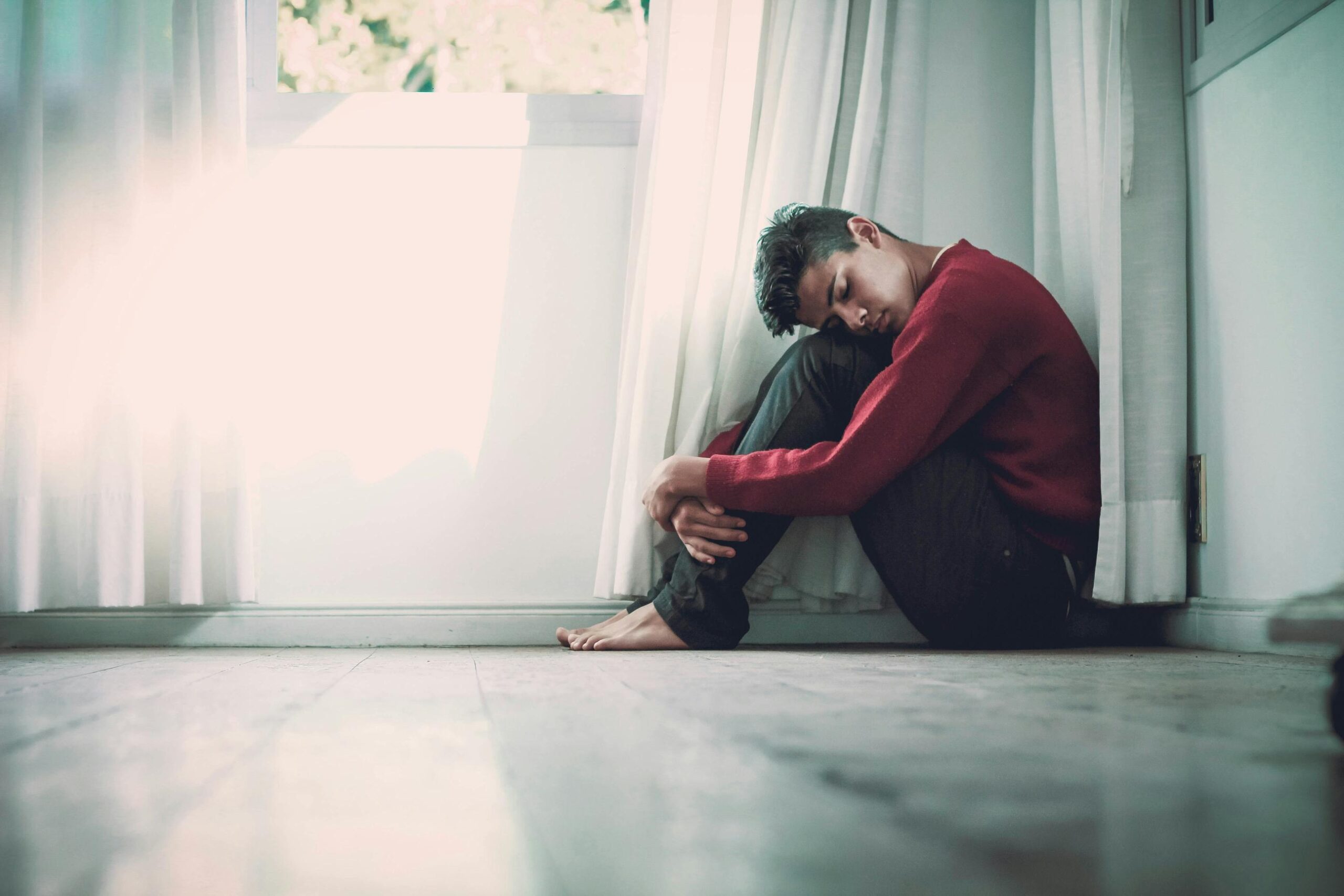 man with anxiety curled up in the corner of the room