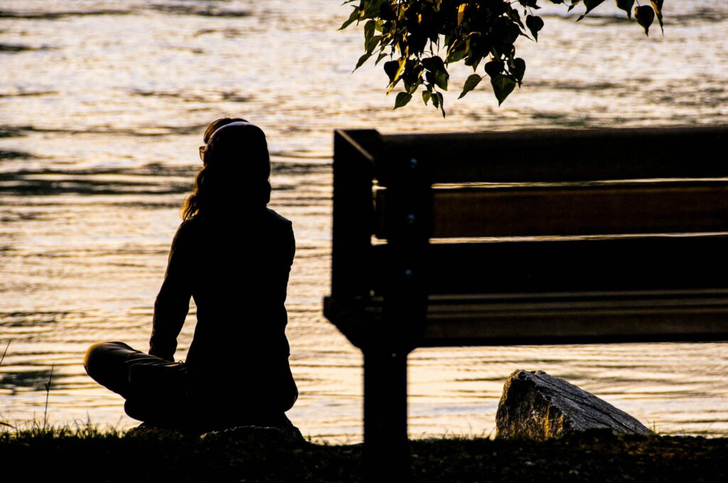 woman meditating by the water to reduce anxiety